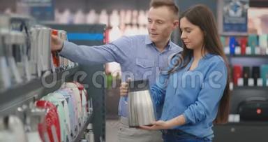 电器商店的年轻夫妇在柜台上选择了一个电热水壶